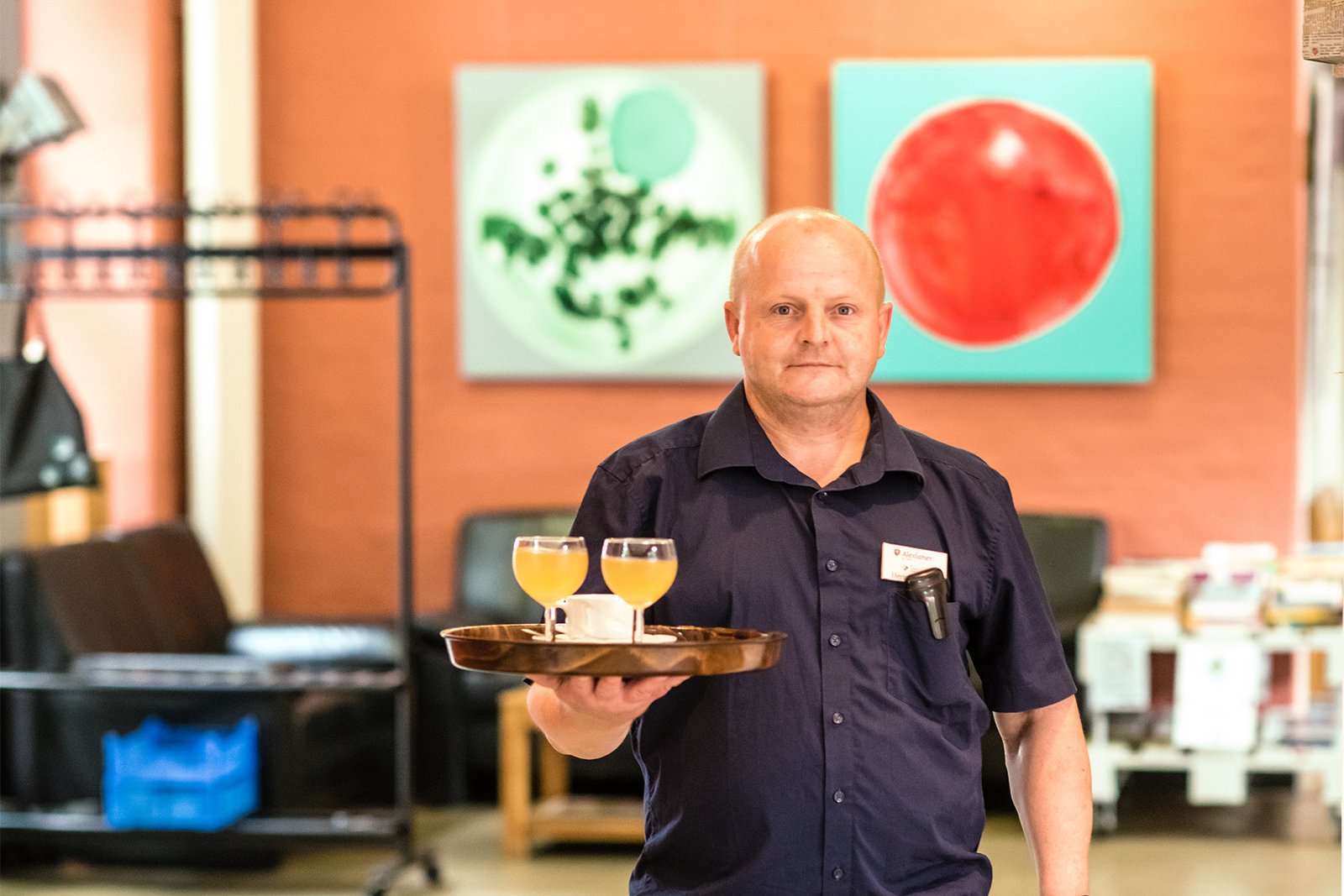 Ein Mann mit einem Tablett mit Getränken bedient in einem Cafe