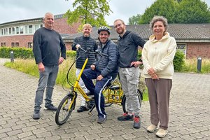 Team und Bewohner der Wohngruppe Leo stehen am e-Dreirad 