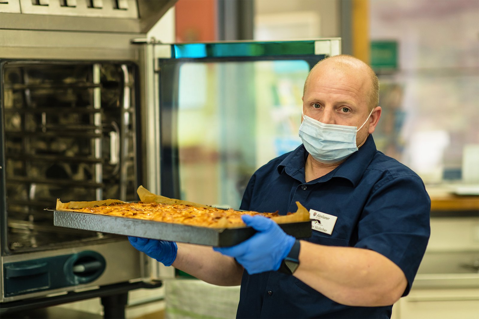 ein Mann holt ein Blech Apfelkuchen aus dem Ofen