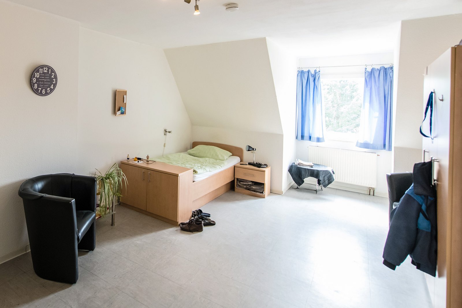 Ein helles Schlafzimmer mit einem Bett, Schrank und Fenser